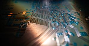 A detailed close-up of a computer circuit board with copper pathways and small electronic components illuminated by soft light.